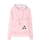 Flauschiger Samojede-Welpe sitzt bequem in einem Hoodie-Beutel.